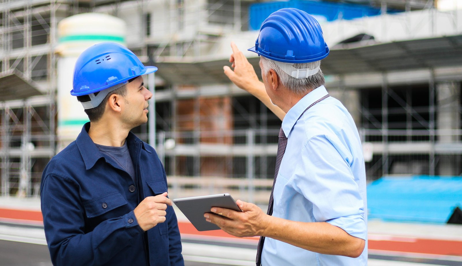 Two architect developers reviewing building plans at construction site