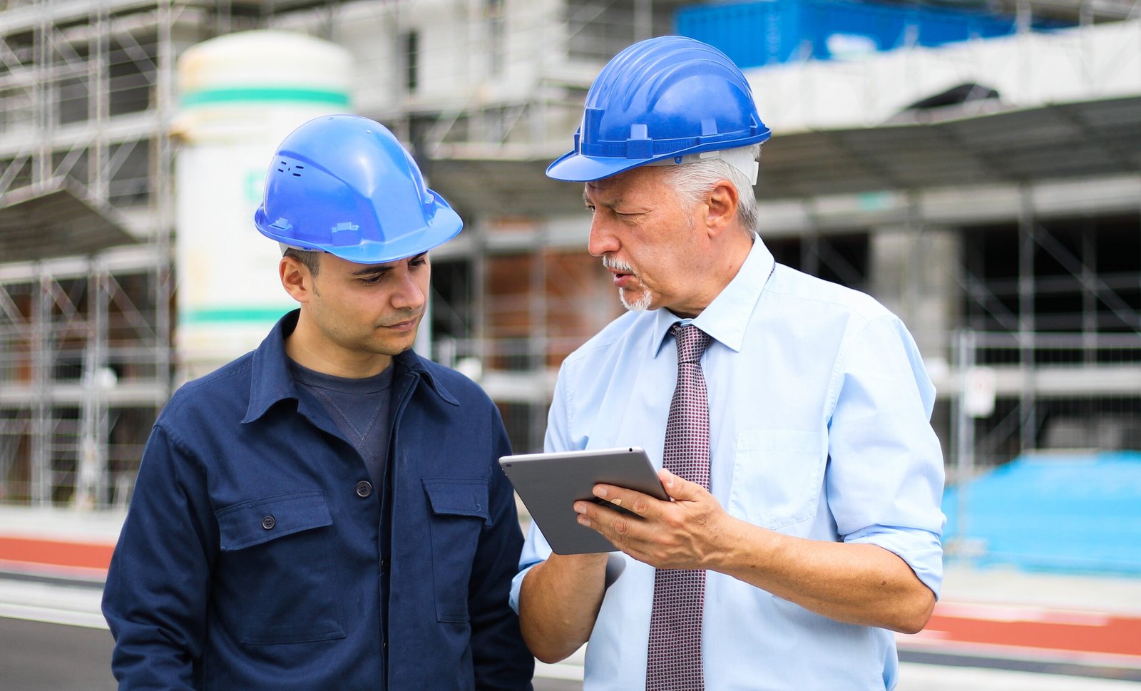 Two architect developers reviewing building plans at construction site