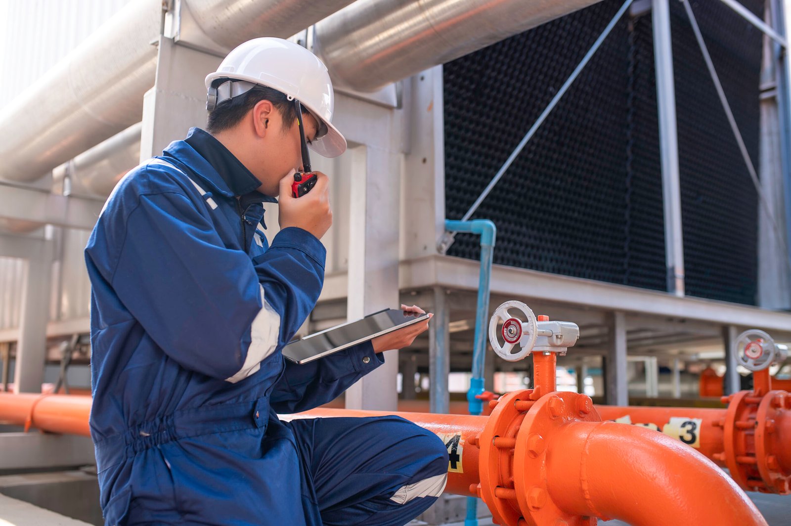 Young engineer working at large factory,Technician in protective uniform and with hardhat  checking temperature in pipes